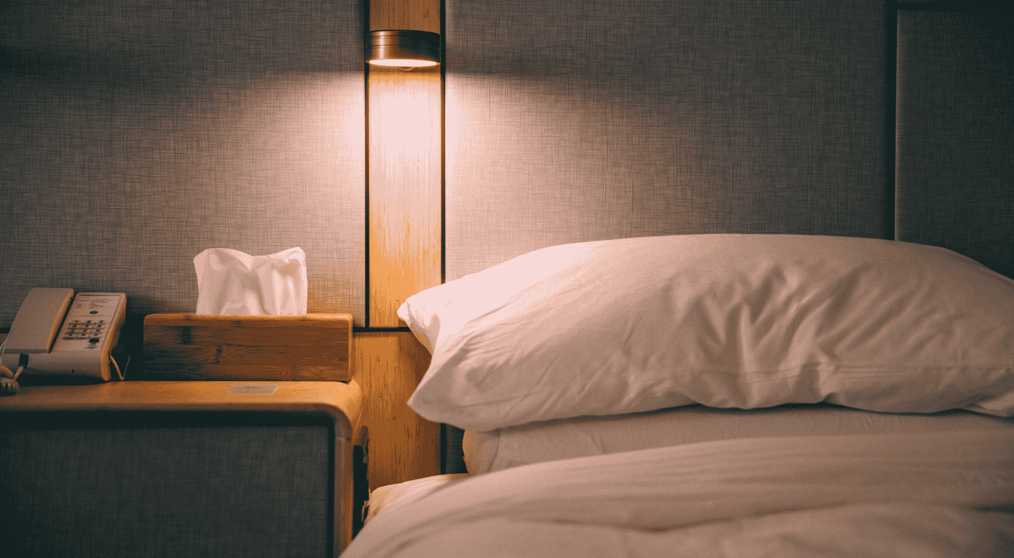 Bedroom scene with a bed, nightstand, and lamp.